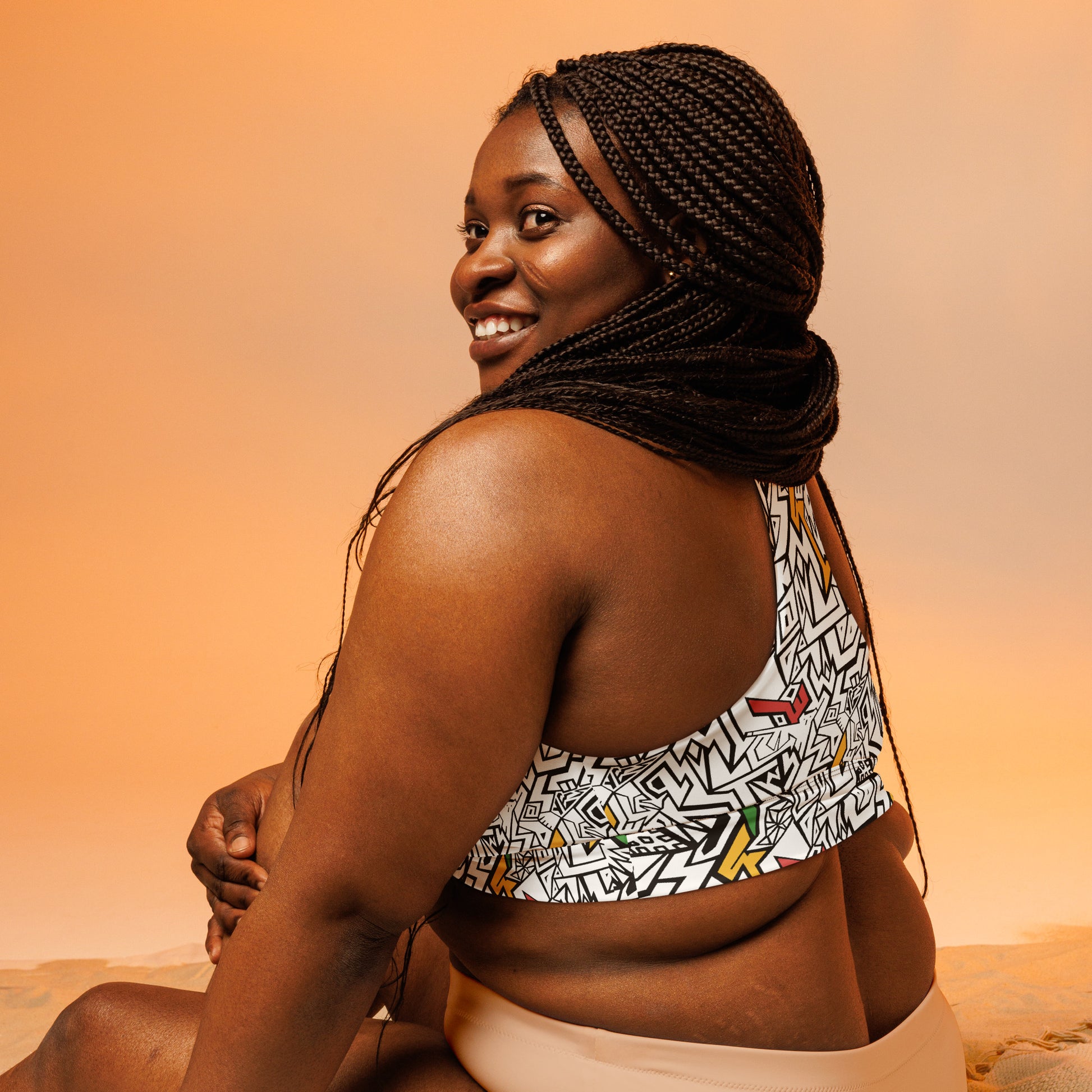 Black, white, red, gold and green psychedelic plus size sports bra with hidden “Smile At Life” message – exclusive sustainable design by Fowl Plays Print Emporium.