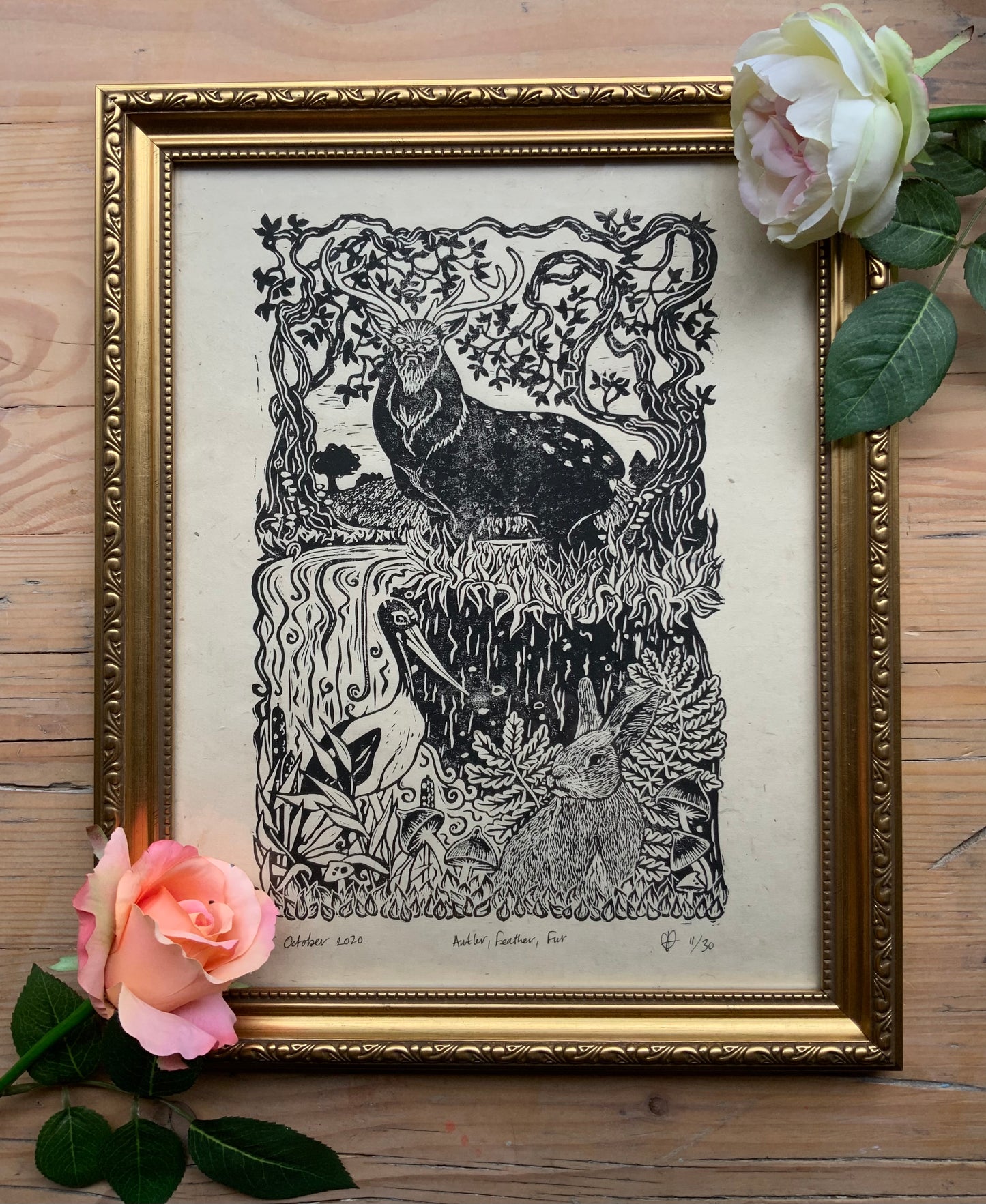 Framed Antler, Feather, Fur print in a gold swirl frame with flowers around the edges.